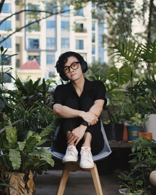 Trọng ngồi giữa những chậu cây trên ban công
